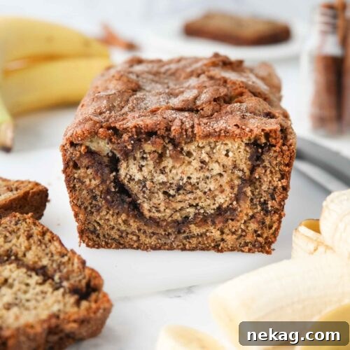 A close-up view of a slice of cinnamon swirl banana bread, highlighting the distinct, gooey cinnamon-sugar layer perfectly swirled through the moist banana bread crumb.