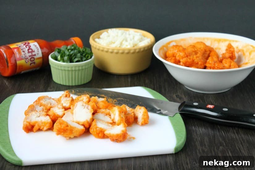 Spreading buffalo sauce generously onto a flatbread base.