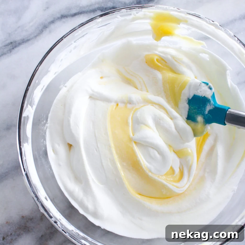 Zesty Lemon Cream Delight 4 Lemon whipped cream being folded into a glass bowl, creating a swirl.