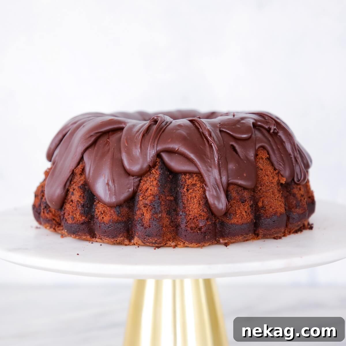 A perfectly baked chocolate zucchini cake presented on an elegant white and gold cake stand.