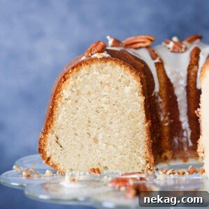 A thick, enticing slice of Maple Pound Cake with a generous drizzle of maple glaze and toasted pecans.