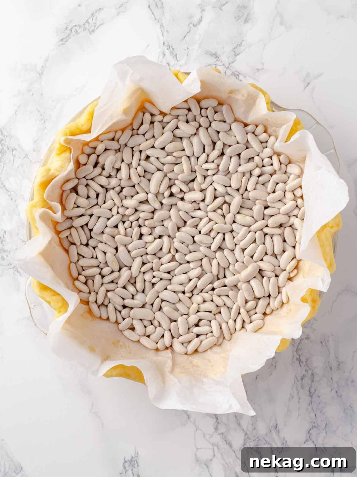 Blind baking Pâte Sucrée with baking beans, showing the weights keeping the crust in shape.