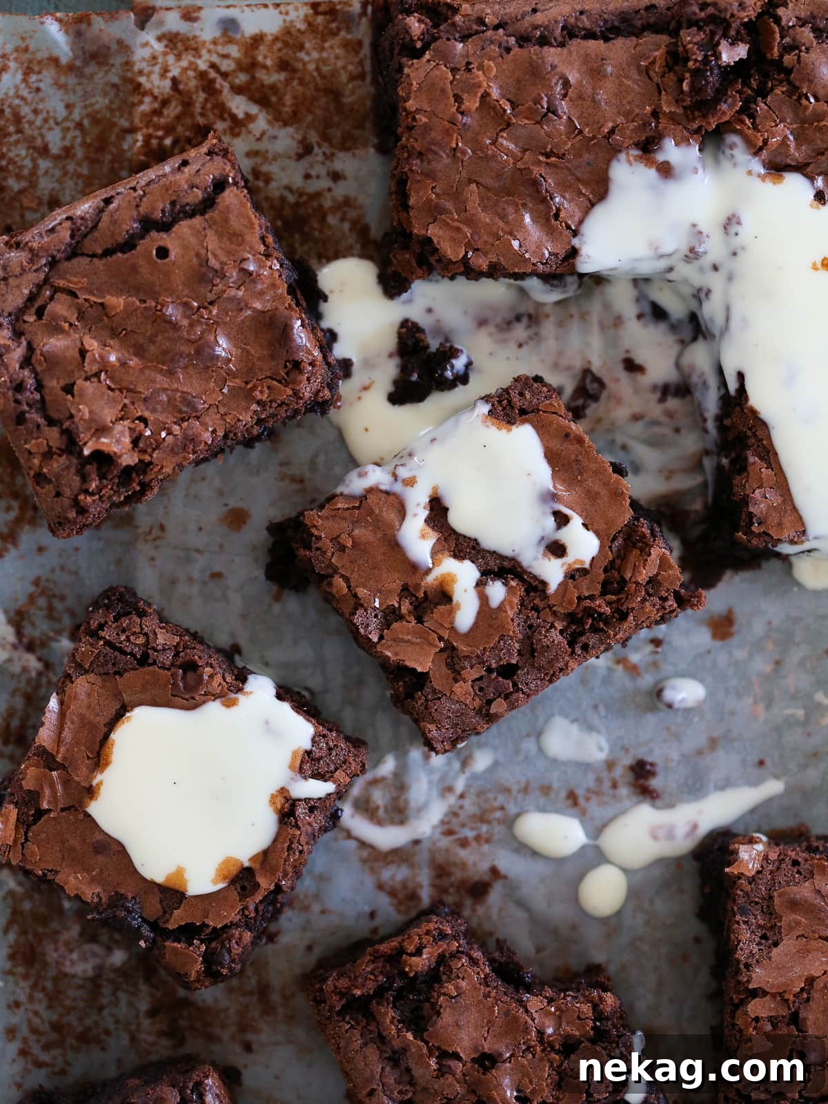 Ultimate Fudgy Brownie Perfection 14 Brownies covered with shiny creme anglaise, cut into squares on parchment paper.