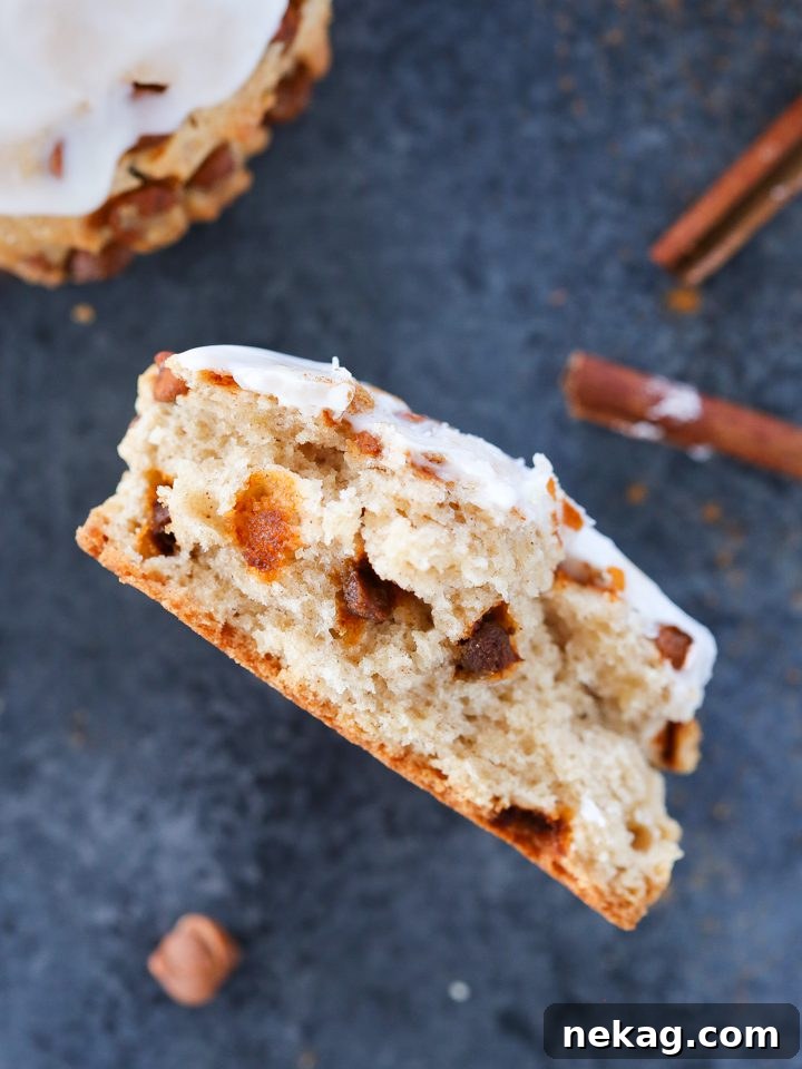 Sweet Cinnamon Swirl Scones 2 A freshly baked cinnamon scone with visible cinnamon chips sits on a rustic blue background, inviting a warm and comforting feeling.