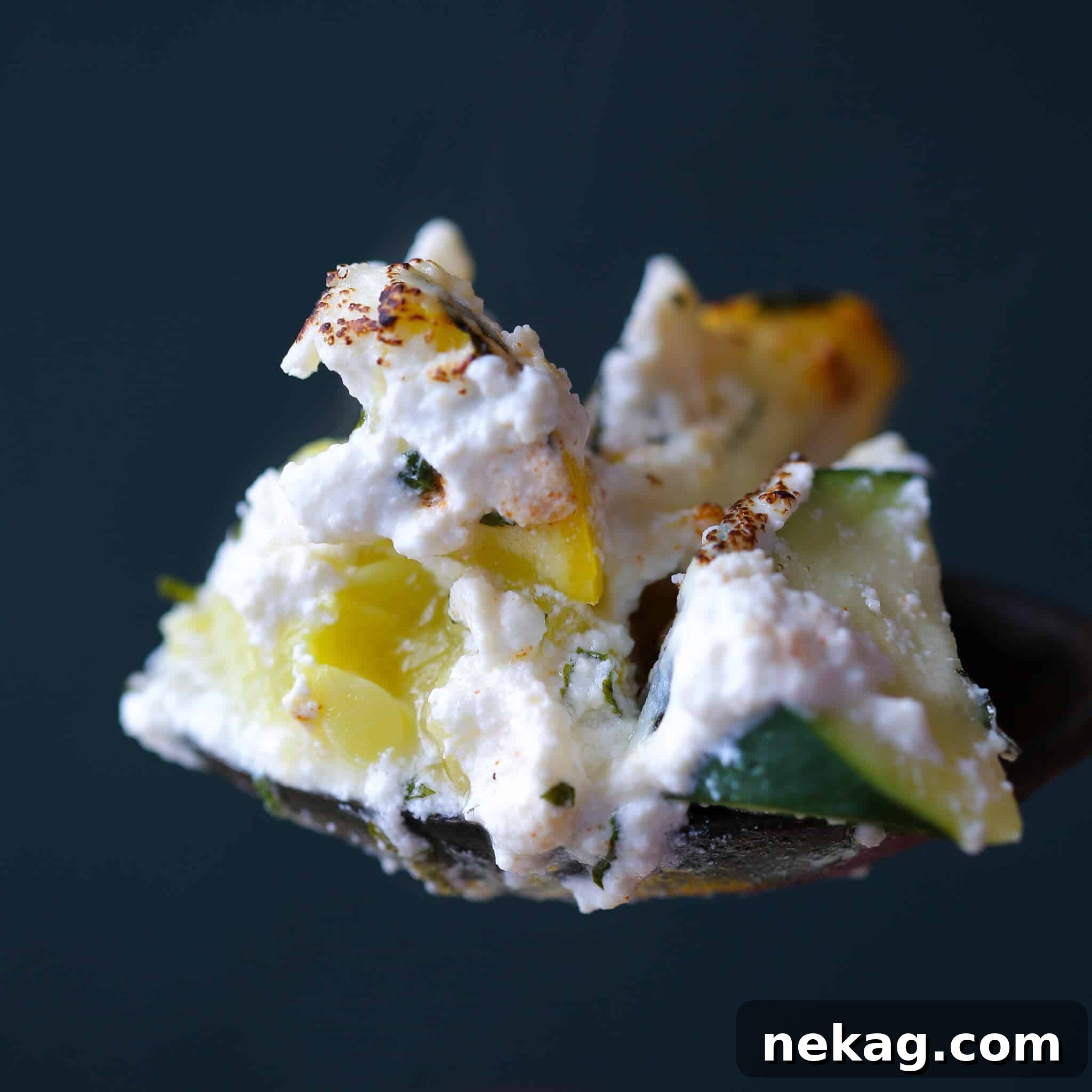 A serving spoon lifts a generous portion of Zucchini Ricotta Casserole from the dish