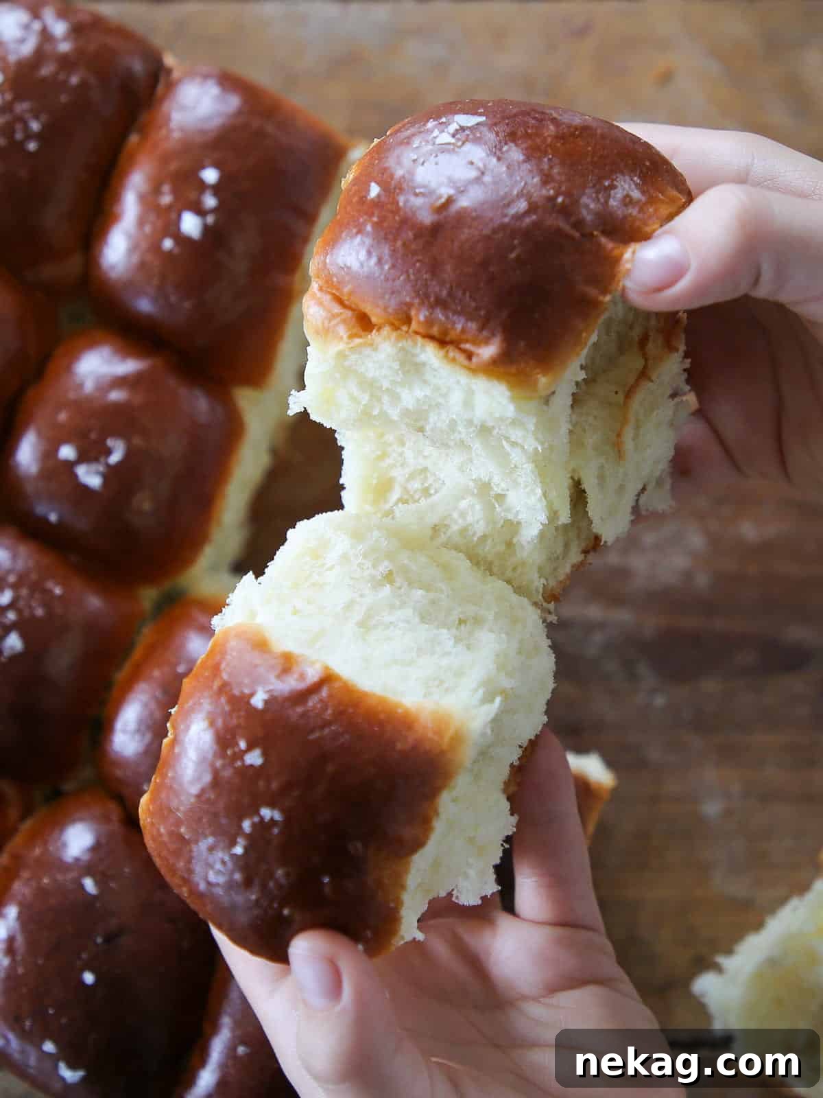 Pillowy Potato Rolls 2 Breaking a warm, fluffy potato roll by hand to reveal its tender interior.