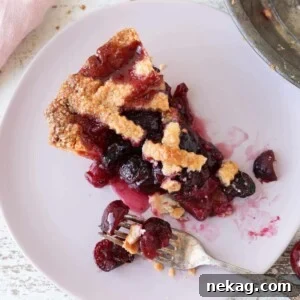 Thanksgiving Traditions A Recipe and Menu Collection 17 A delectable slice of Cherry Pie with an Almond Crust, featuring a beautiful lattice top, ready to be enjoyed.