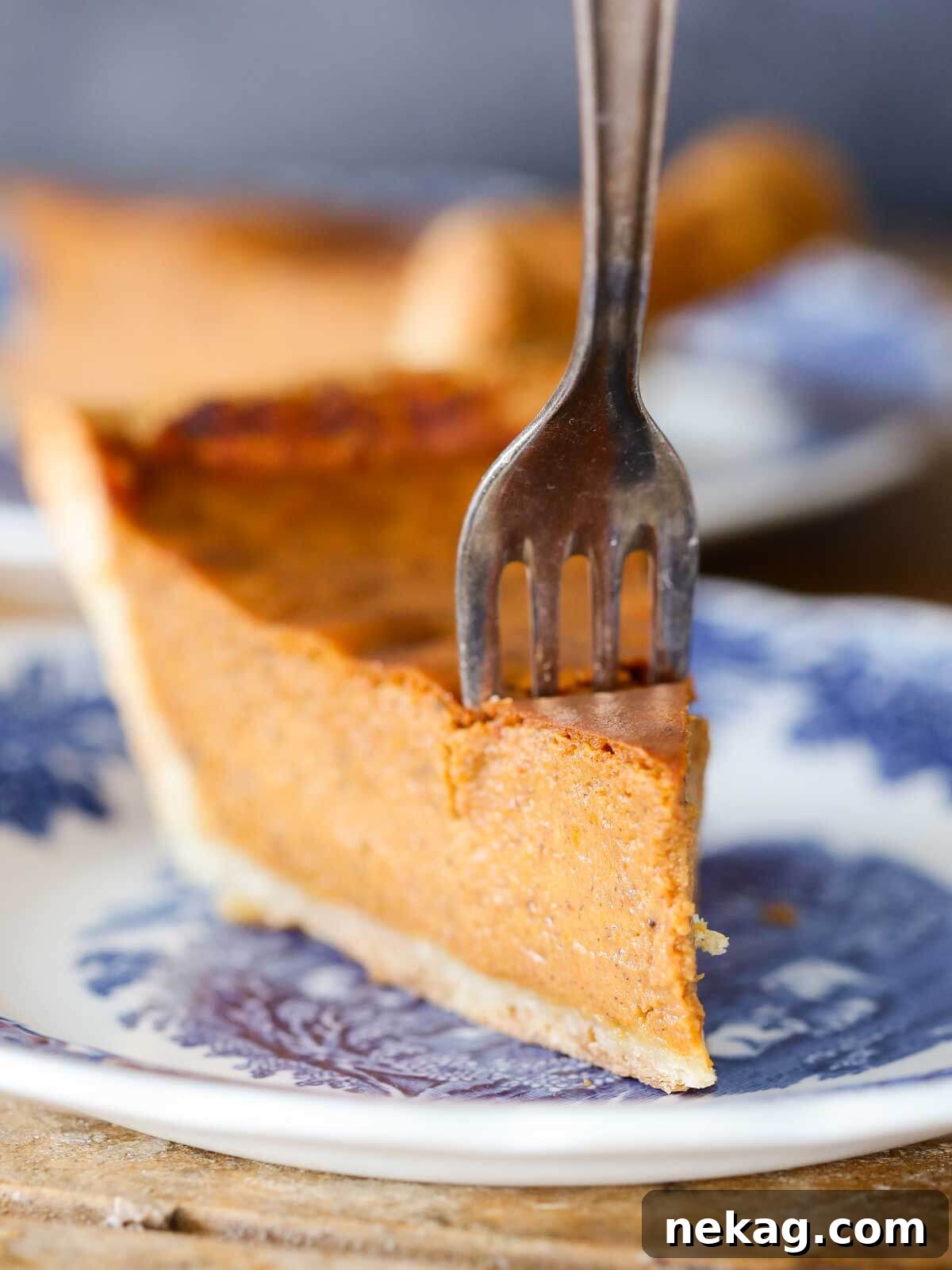 Thanksgiving Traditions A Recipe and Menu Collection 18 A delectable slice of pumpkin pie, a quintessential Thanksgiving dessert, with a fork gently inserted, ready for a bite.