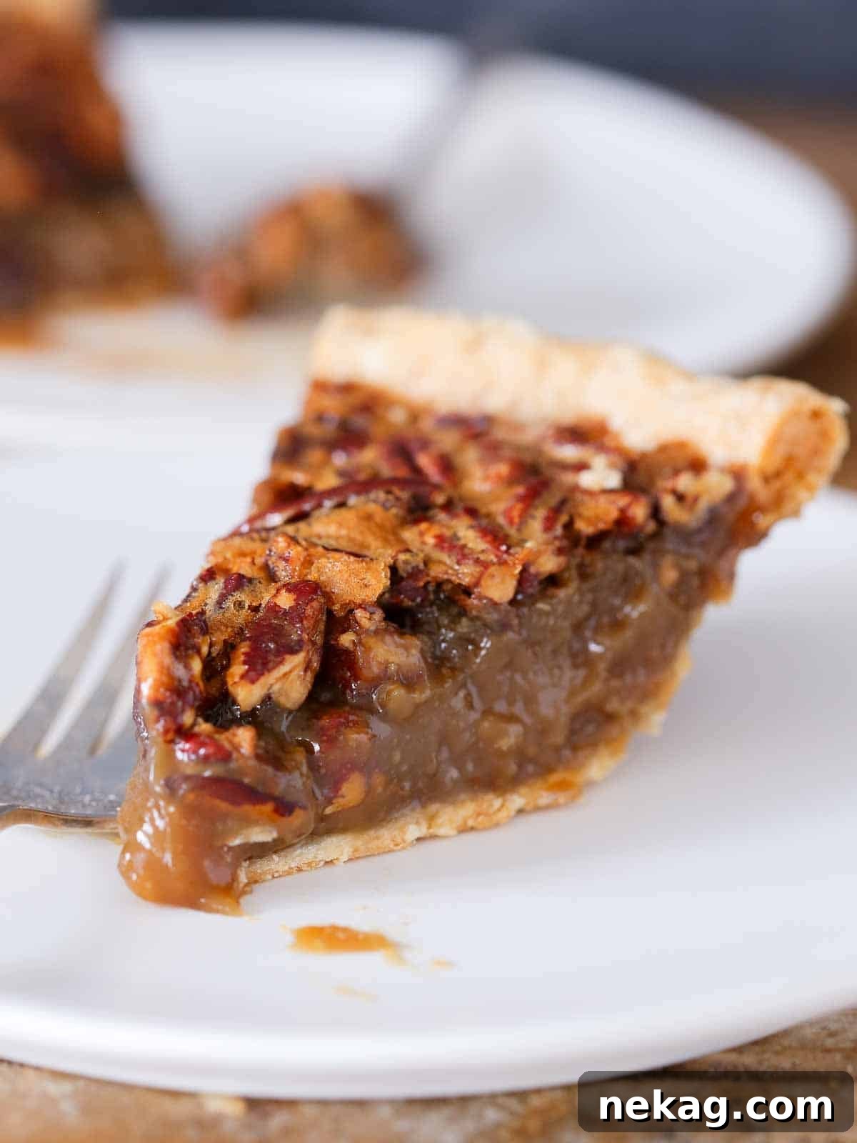 Thanksgiving Traditions A Recipe and Menu Collection 22 A perfectly triangular slice of rich pecan pie, beautifully presented on a pristine white plate, a hallmark of traditional Thanksgiving dessert.