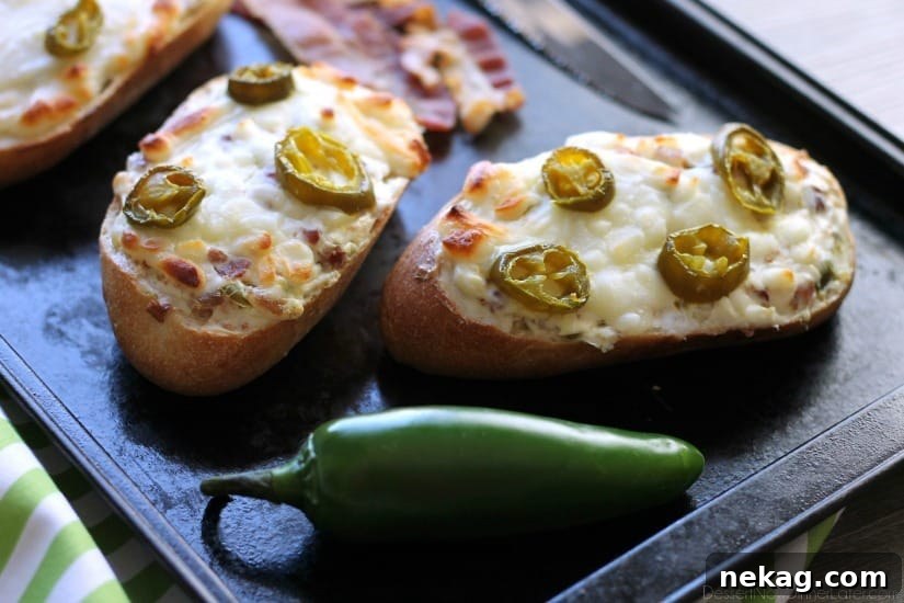 Overhead shot of two halves of Jalapeno Popper Bread, freshly baked, with cheese bubbling and ready to be sliced, on a wooden board.