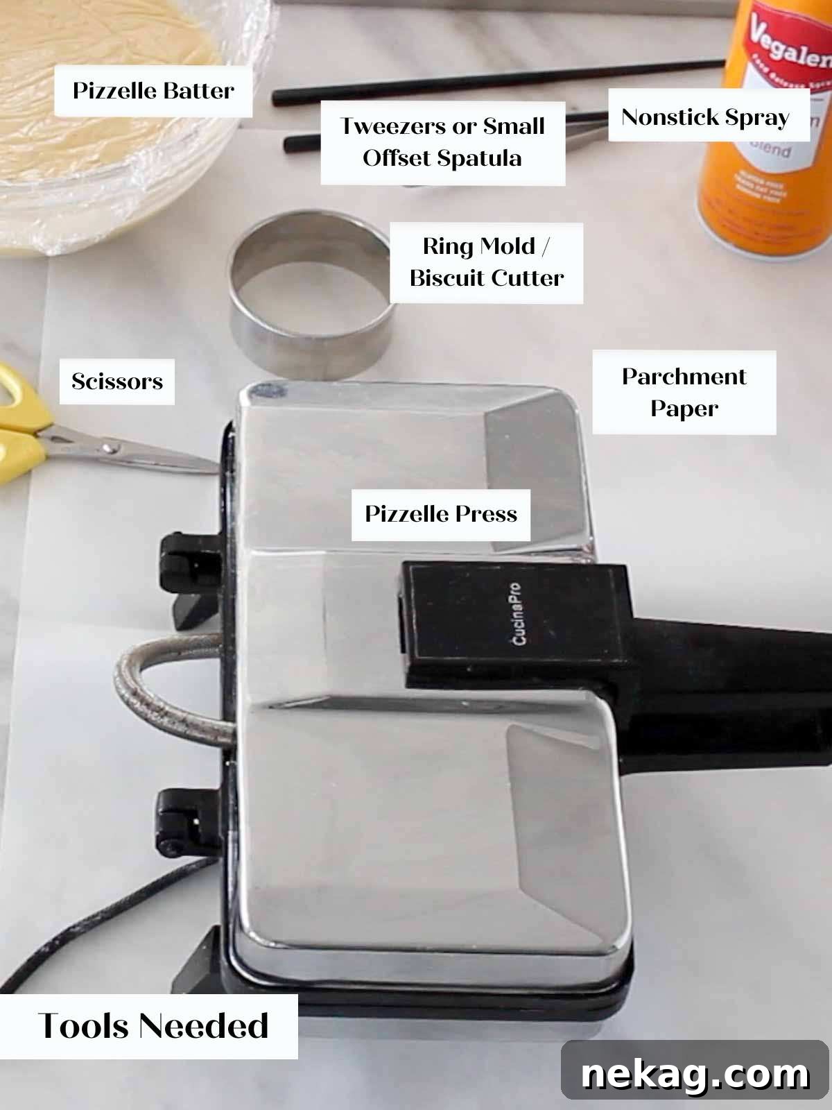 Pizzelle making equipment, including a pizzelle iron, spatula, and measuring tools, arranged on a marble surface.