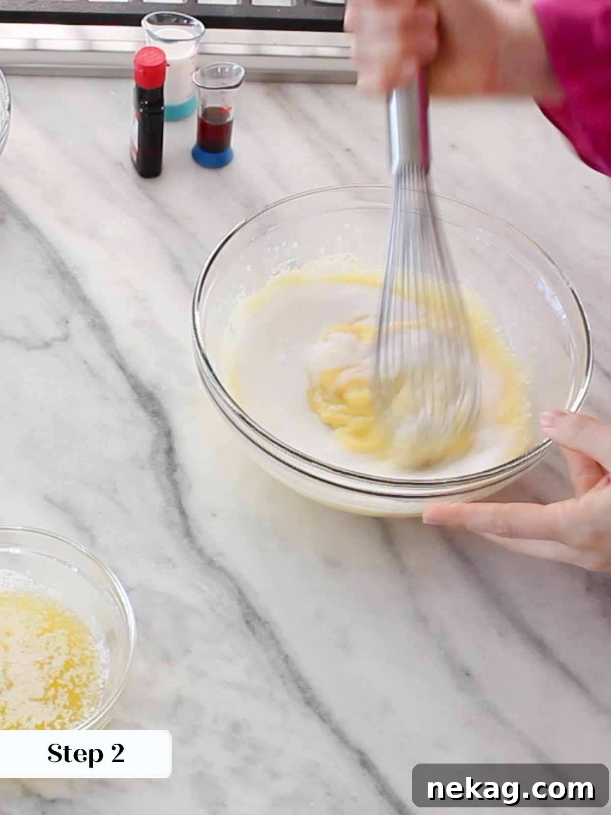 A person whisking batter in a bowl, showing the consistency of the liquid ingredients.