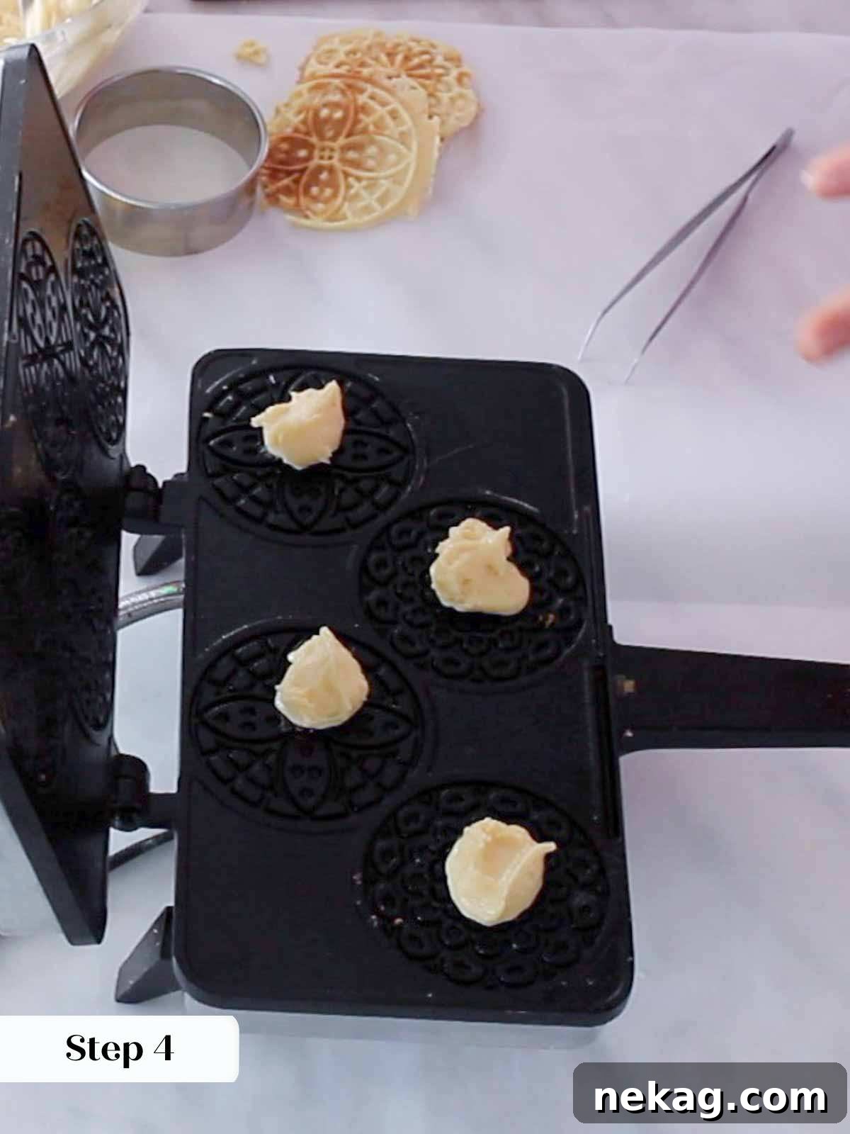 A teaspoon of pizzelle batter being carefully dropped onto the heated pizzelle press.