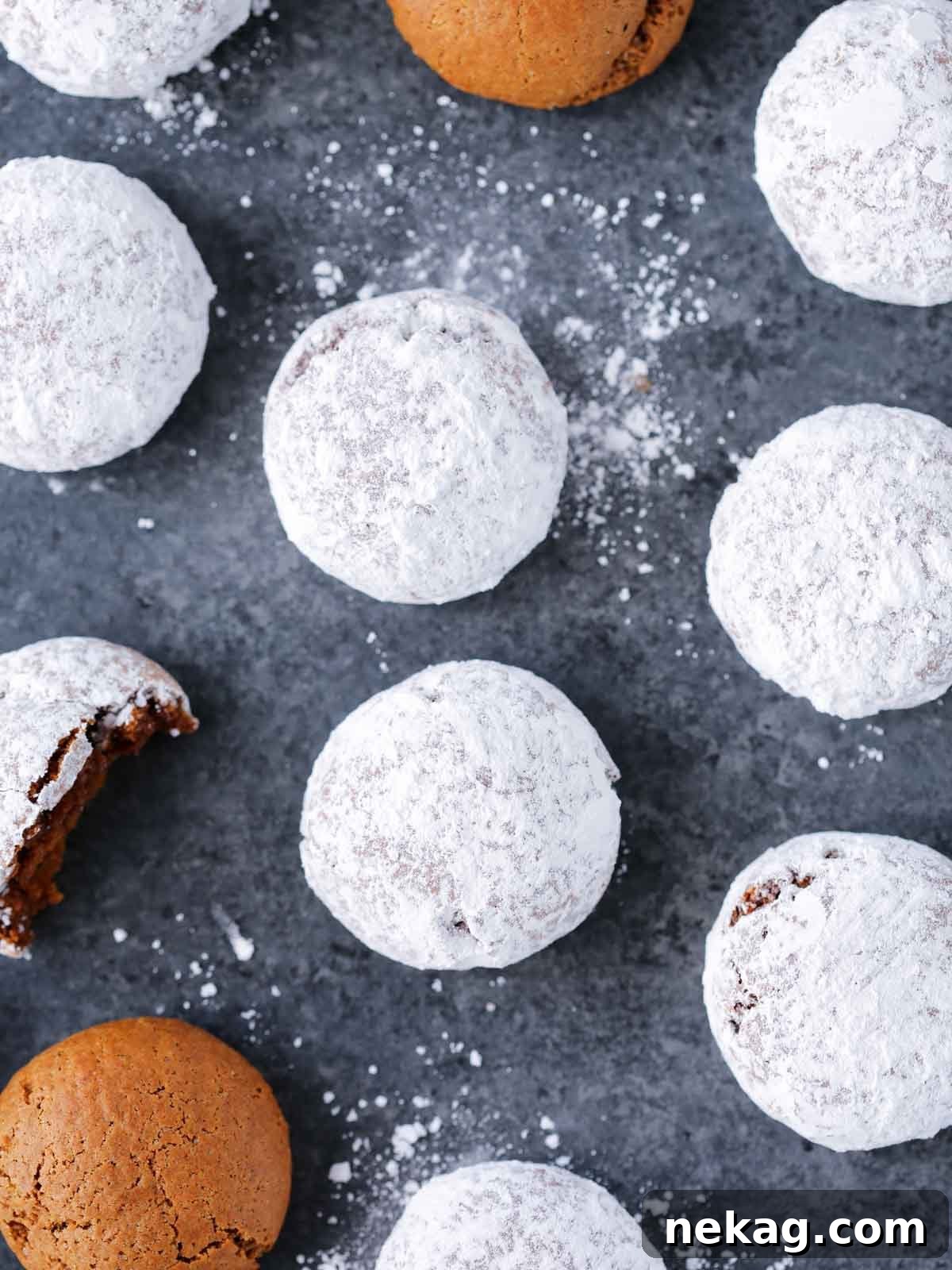 German Christmas Spice Cookies 4 Pfeffernusse cookies generously coated in powdered sugar on a grey surface.