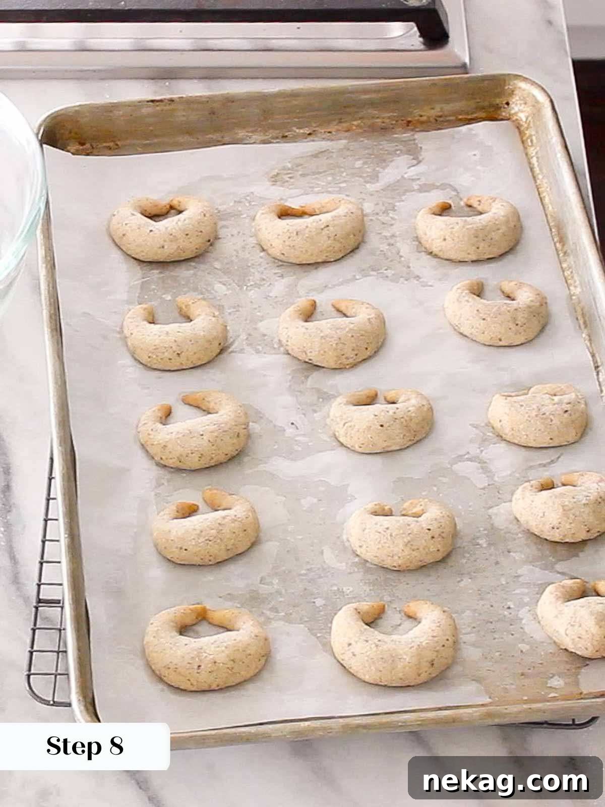 Buttery Almond Crescents 9 baked crescent cookies on baking sheet.