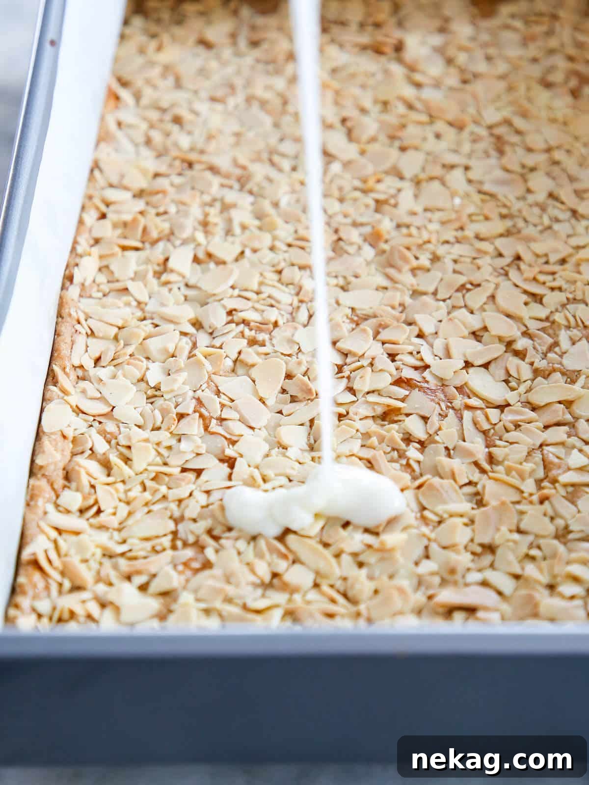 Irresistible Almond Bars 7 White lemon glaze being poured artfully over the warm, crispy almond topping of the bar cookies.