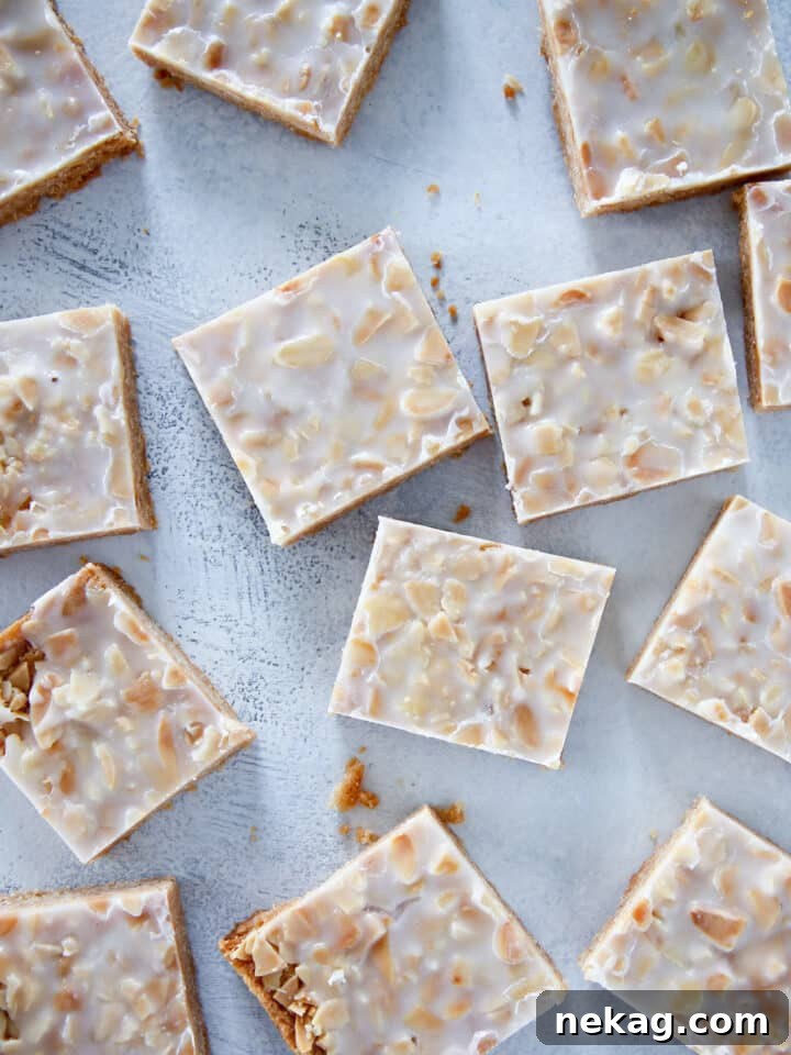 Irresistible Almond Bars 10 Close-up of perfectly sliced crispy almond square cookies arranged on a light blue background, showing the glaze and nut topping.