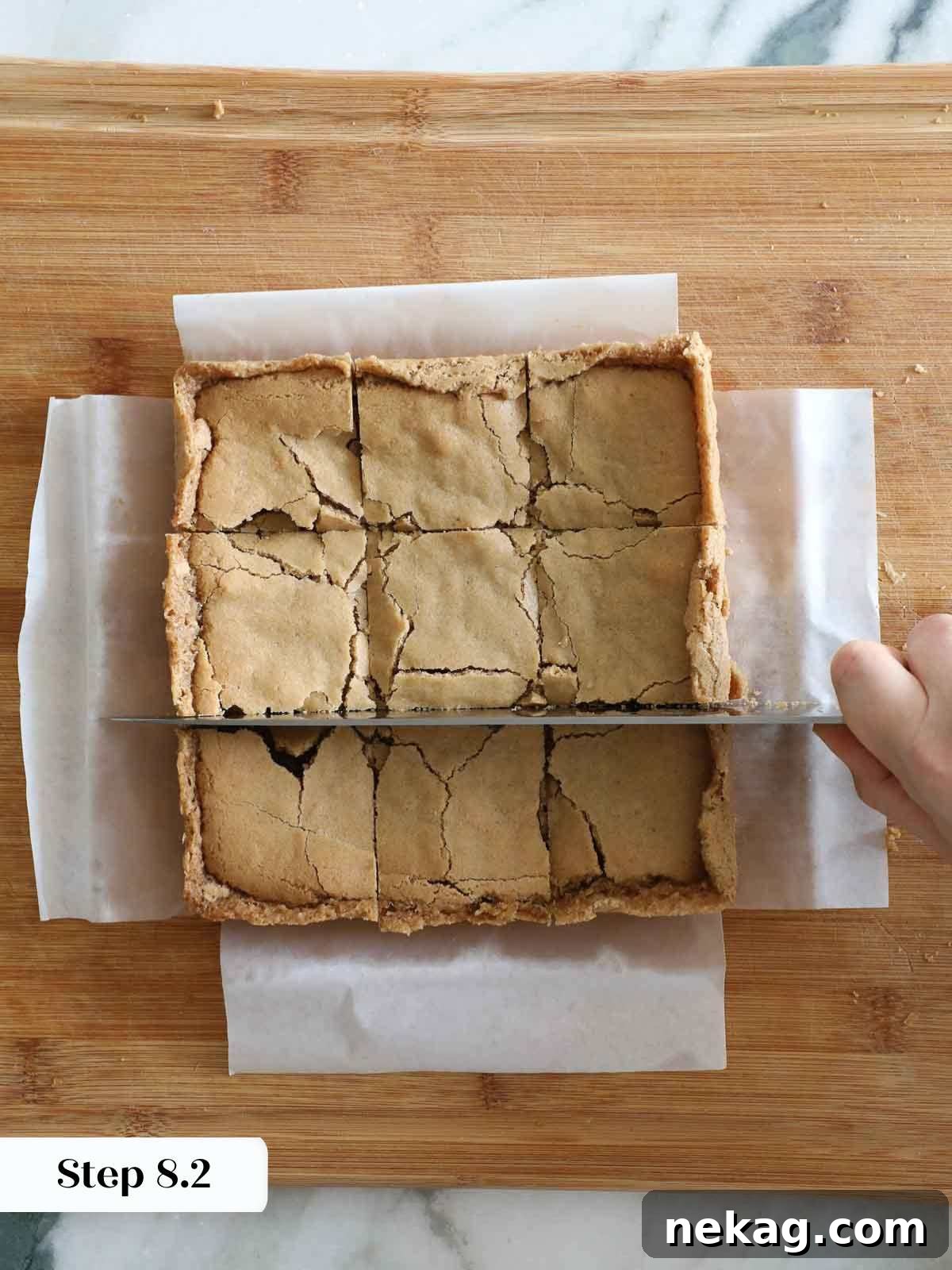 Cutting cooled butterscotch brownies into squares on a cutting board.