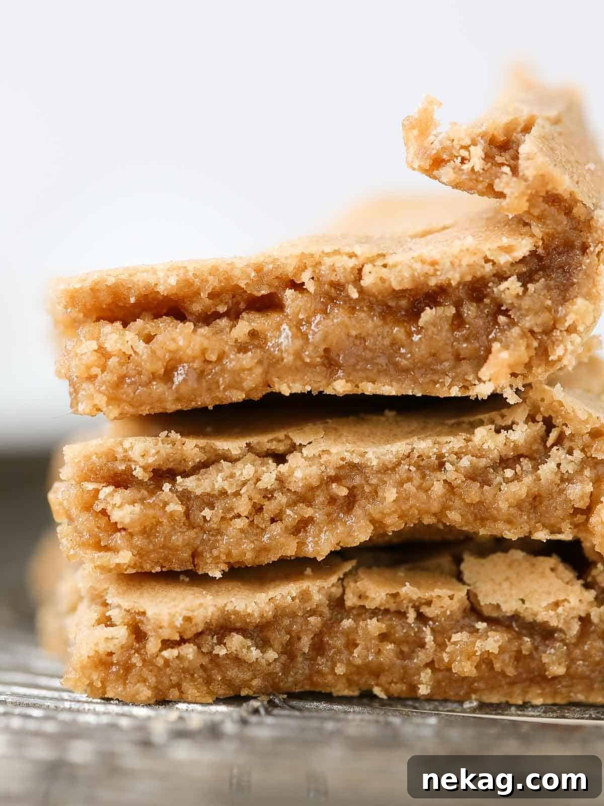 Three butterscotch brownies stacked neatly on a wire cooling rack.