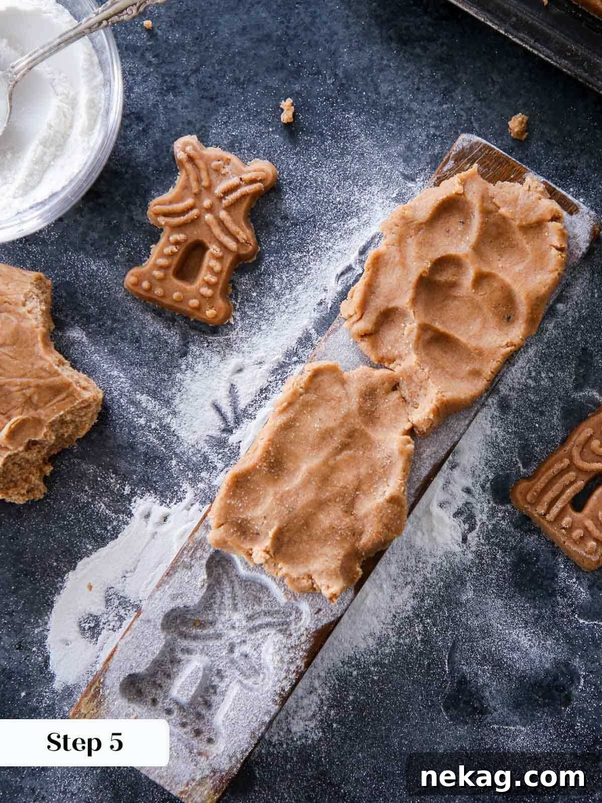 Speculoos dough firmly pressed into a vintage wooden mold, showing the excess to be trimmed.