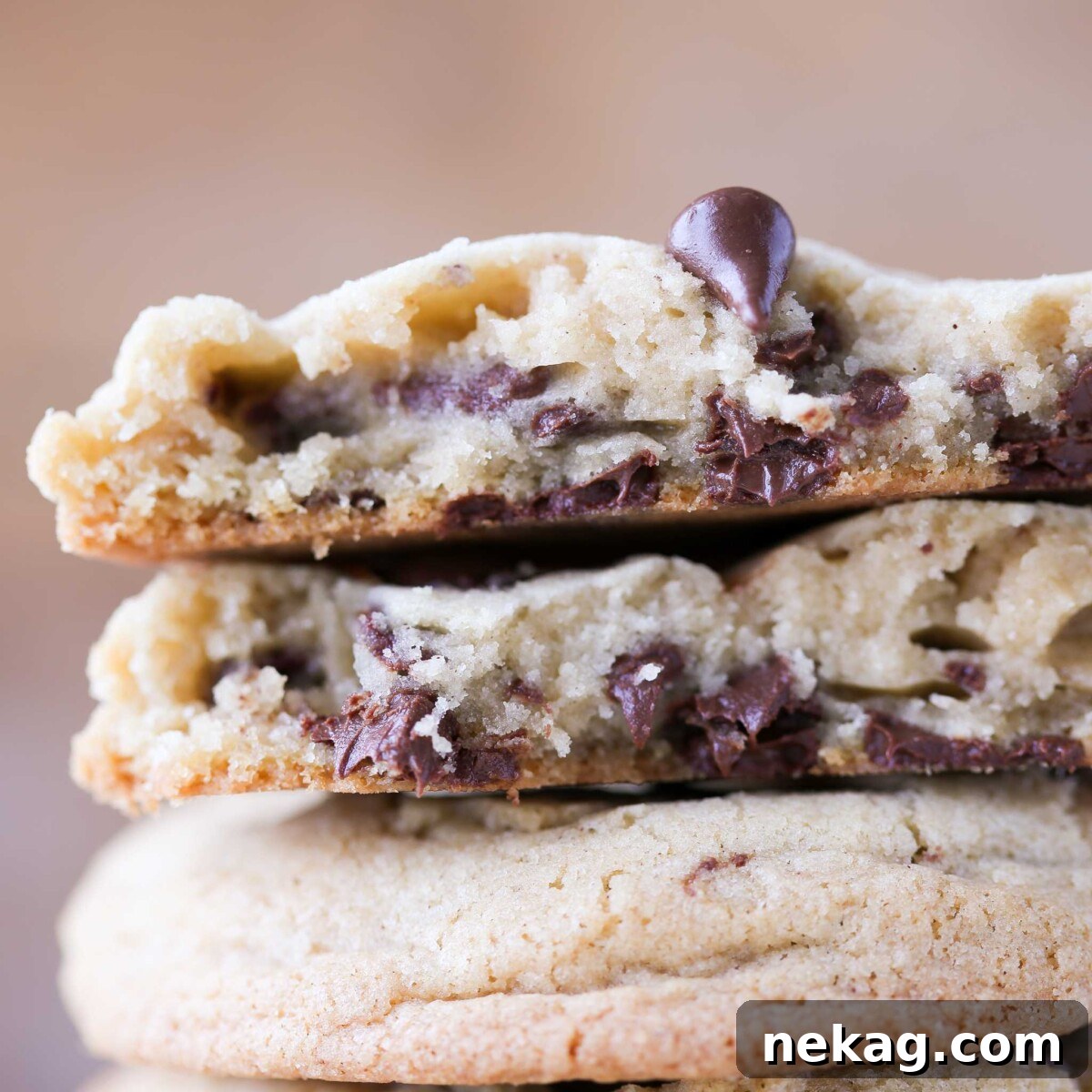 A chocolate chip cookie broken open, revealing melty chocolate chips, highlighting its thick and chewy texture.