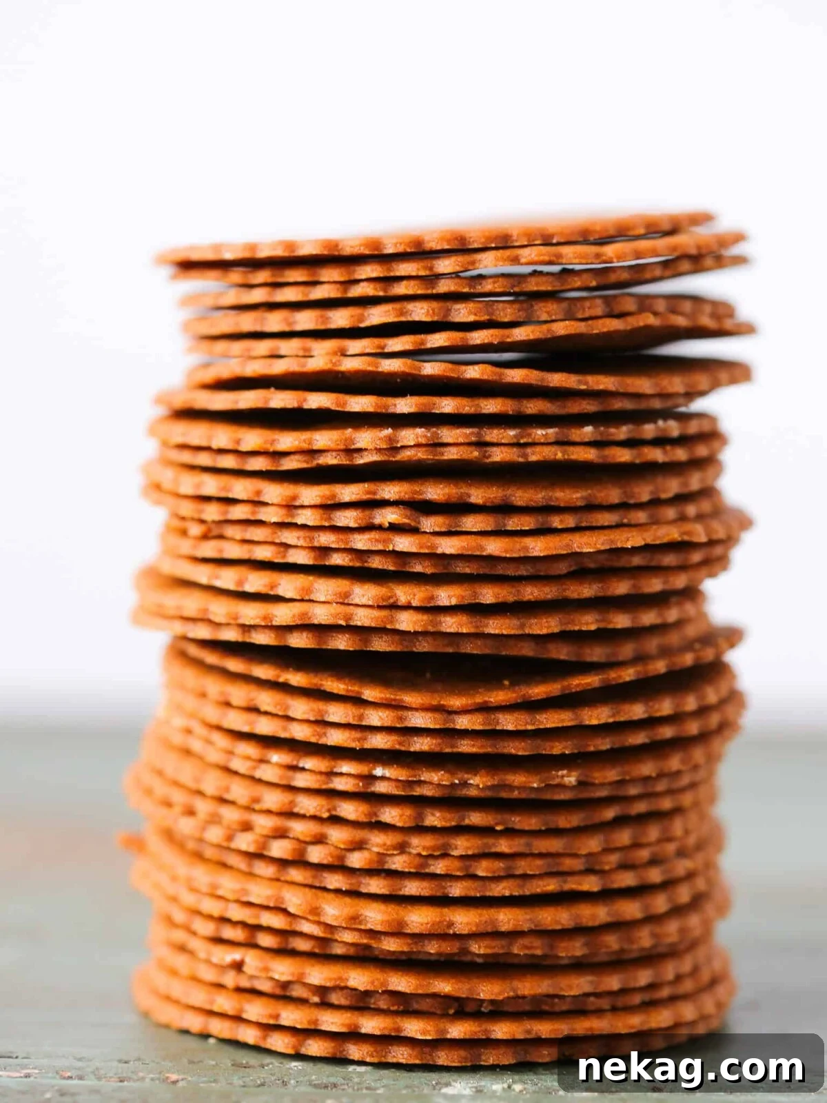 Moravian Christmas Cookies stacked tall on a white background, showcasing their delicate thinness.