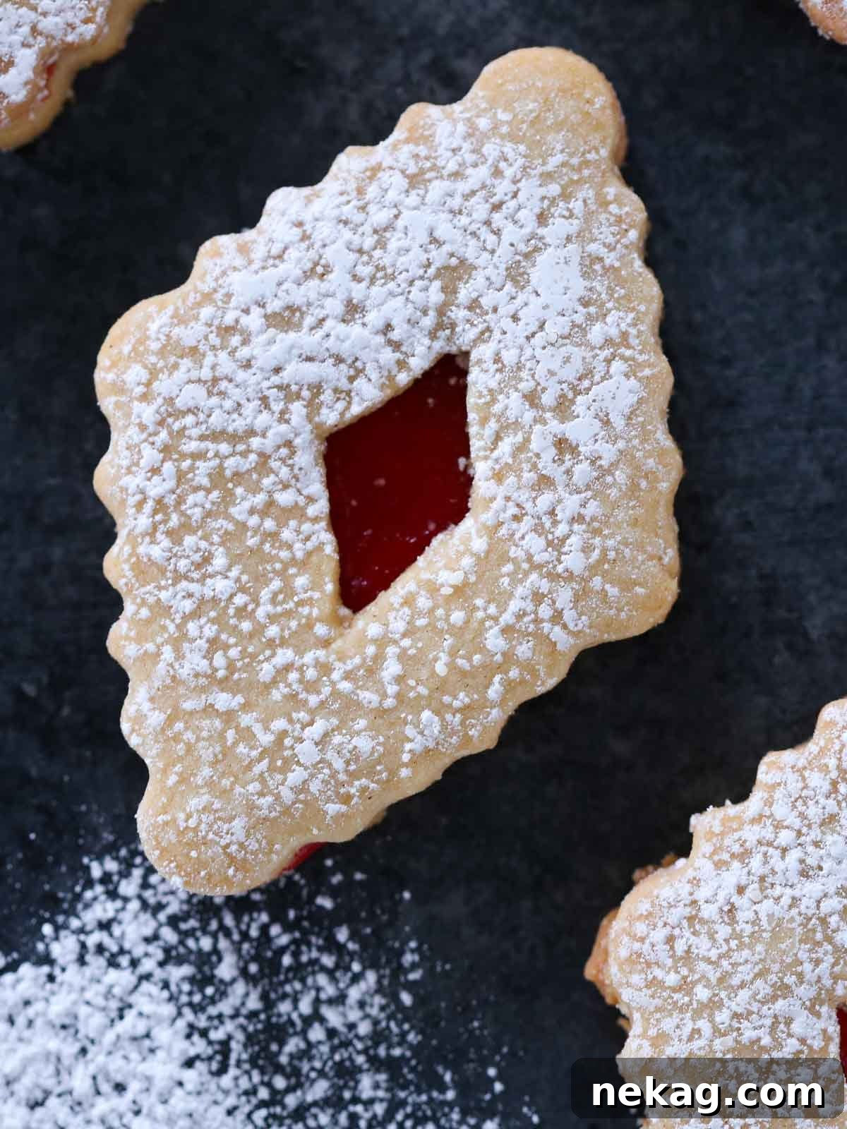 A single beautifully crafted linzer cookie dusted with powdered sugar, showcasing its jam-filled center.