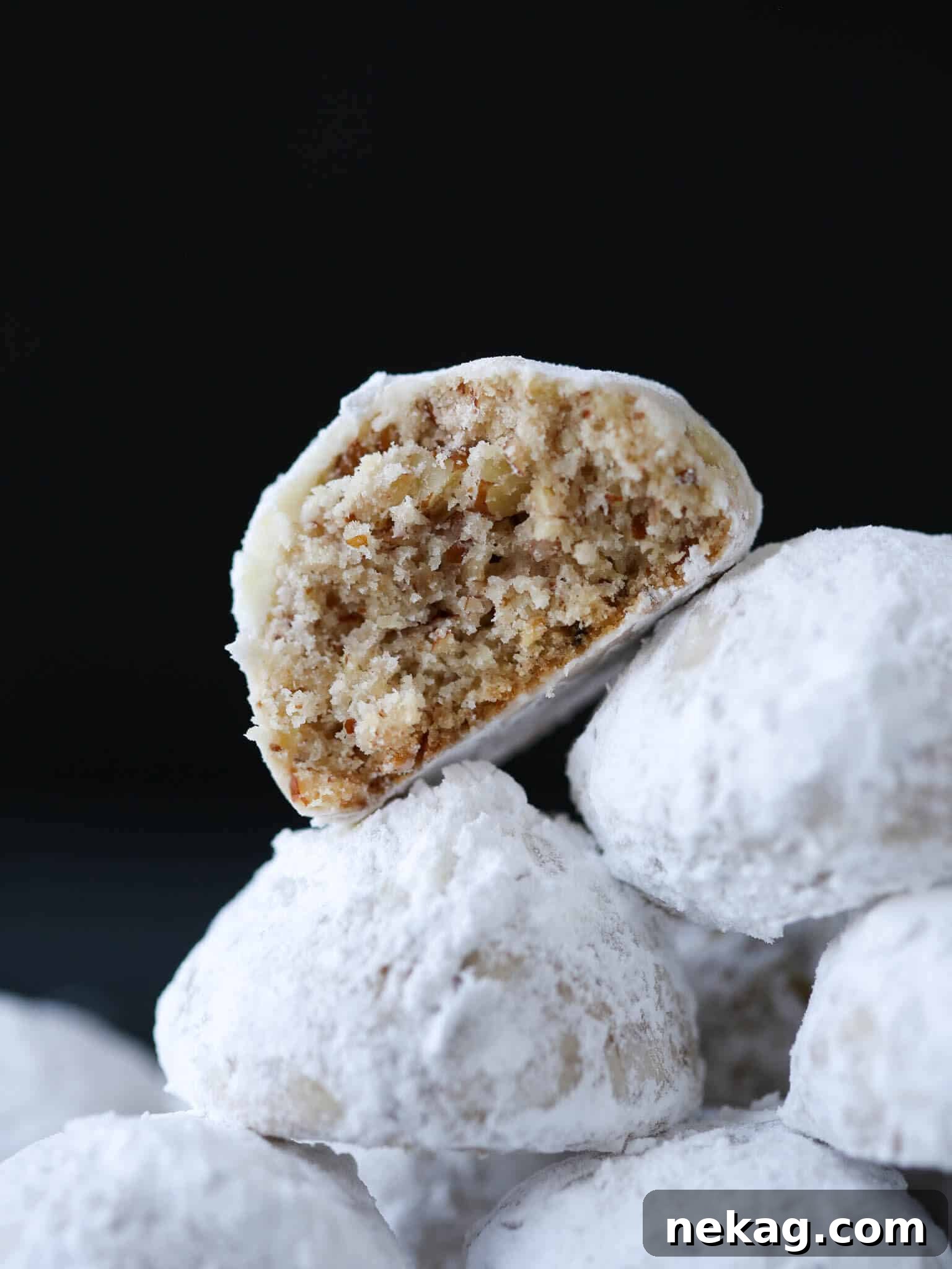 Pecan Snowball Cookies, also known as Russian Tea Cakes, stacked and cut open to show their crumbly texture.