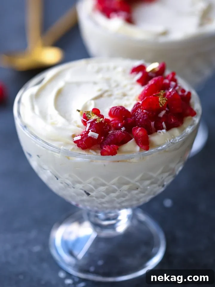 Close-up of creamy White Chocolate Raspberry Mousse with a spoon, highlighting its smooth texture and raspberry garnish.