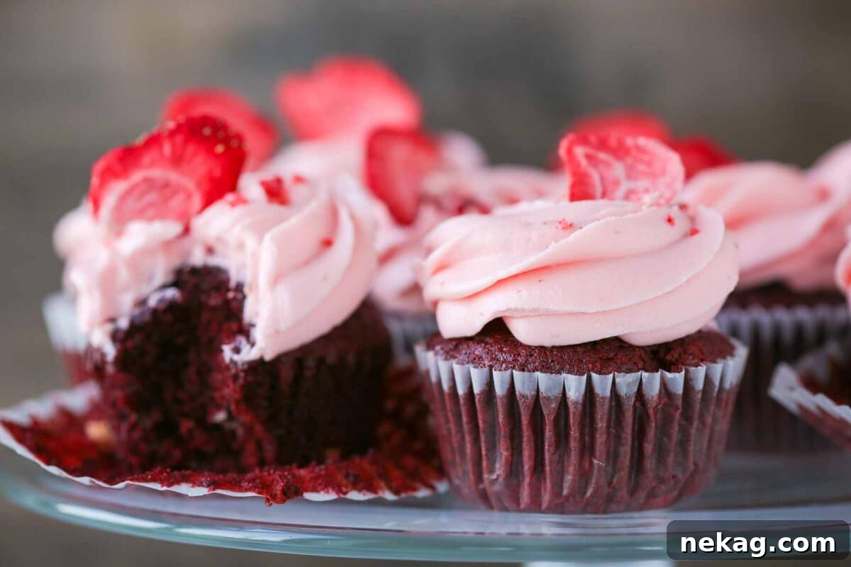 Red velvet cupcakes with pink strawberry cream cheese frosting, beautifully piped.