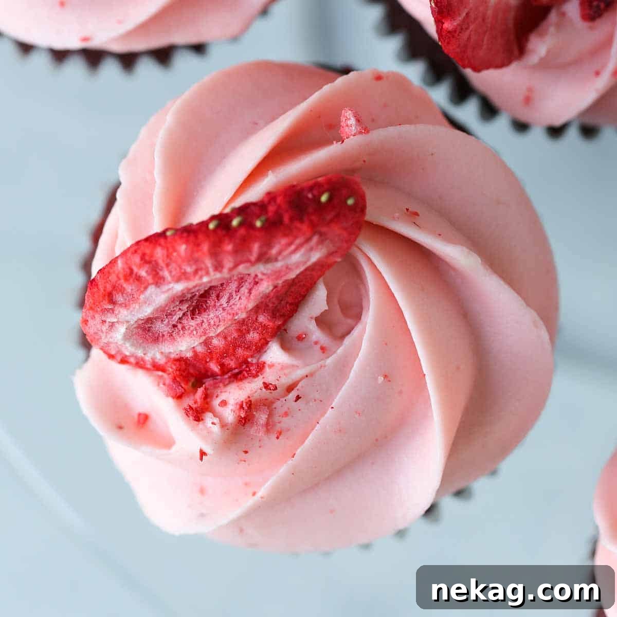 A single red velvet cupcake with strawberry cream cheese buttercream on a marble countertop, ready to be enjoyed.