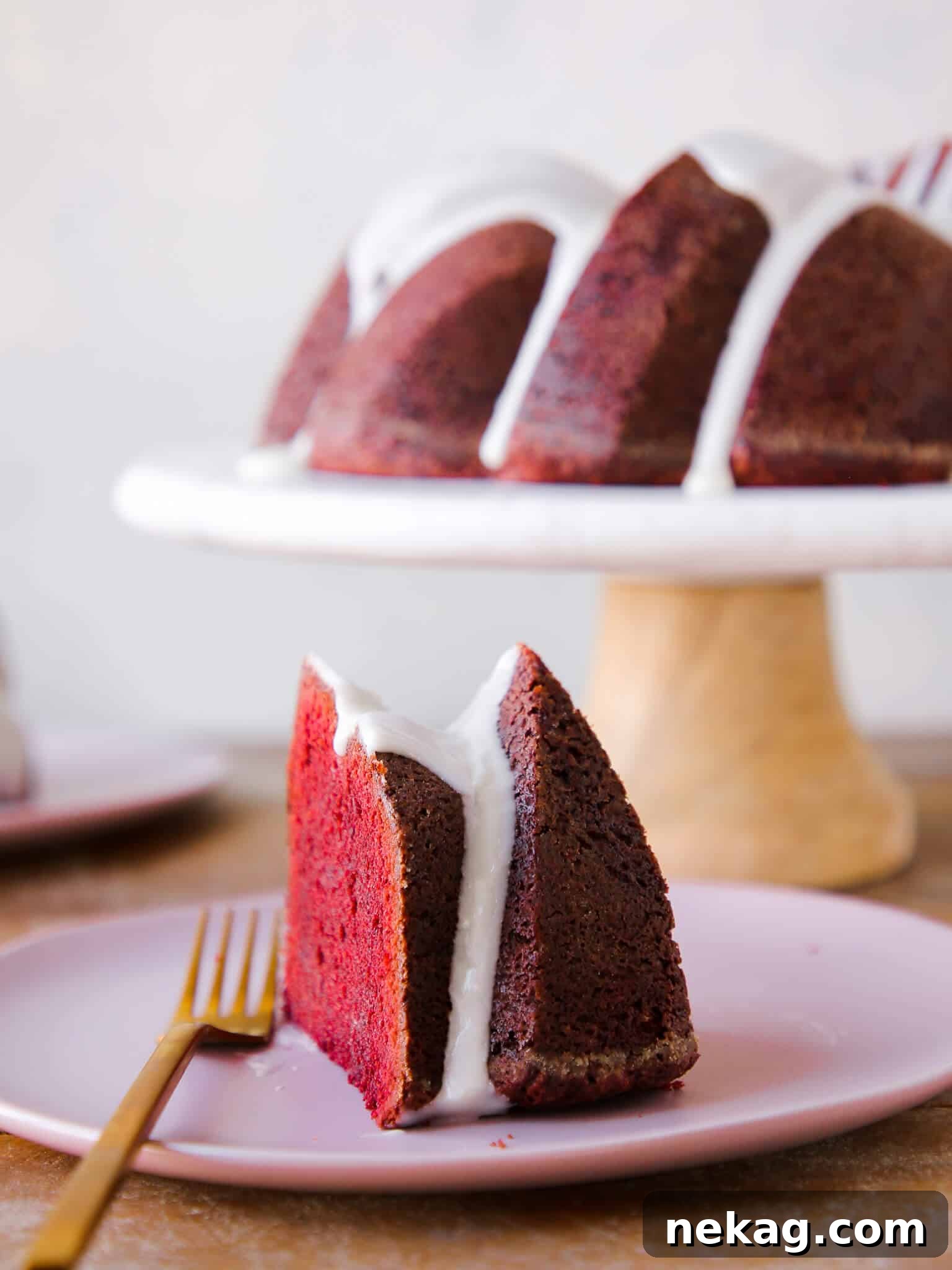 Velvety Crimson Pound Cake 2 A slice of Red Velvet Pound Cake with cream cheese glaze, showing a moist interior, with the whole cake in the background. Perfect for Valentine's Day Desserts.