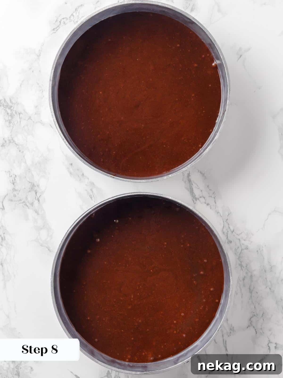 Two round cake pans, perfectly prepared and filled with rich chocolate cake batter, evenly distributed and ready for the oven.