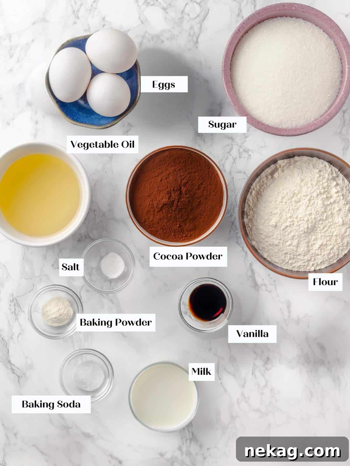 All the necessary ingredients for a delicious chocolate cake, neatly arranged on a pristine white kitchen counter, ready for mixing and baking.