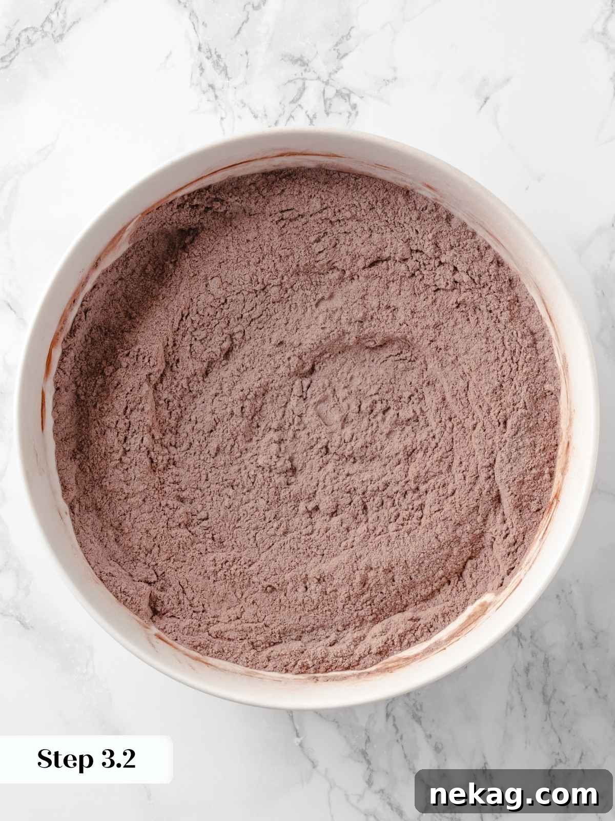 A mixing bowl with thoroughly whisked dry ingredients for the chocolate cake, showing a uniform blend of flour, cocoa, and leavening agents.