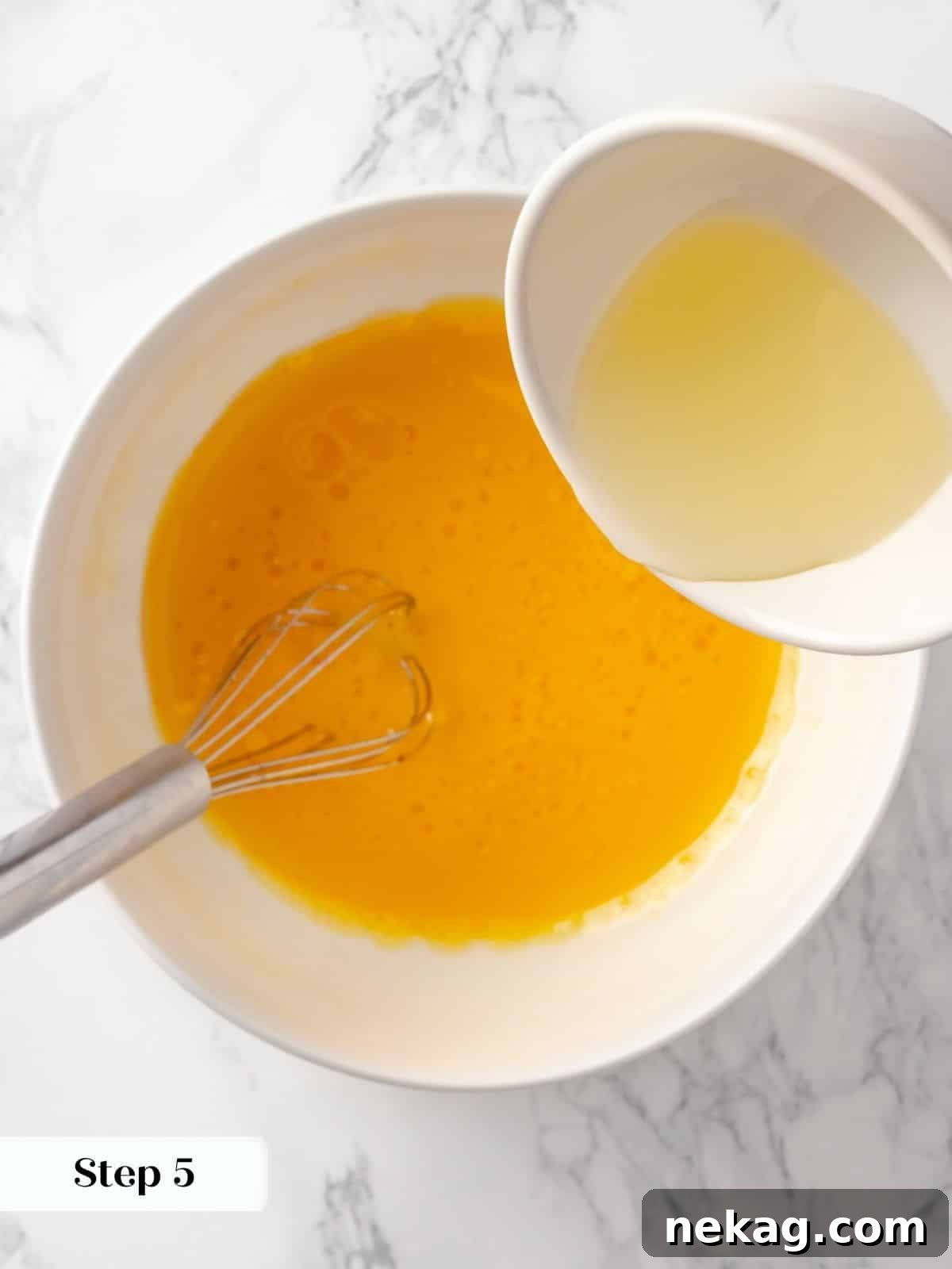 Canola oil being gently poured into the whisked wet ingredients, illustrating the emulsion process for a super moist cake.