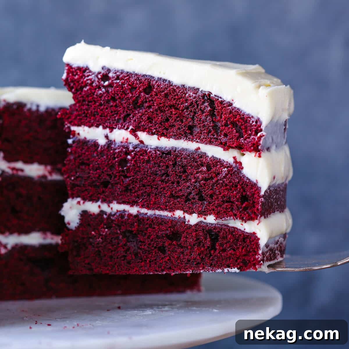 Red Velvet Layer Cake with Cream Cheese Buttercream slice on cake server, ready to be enjoyed.