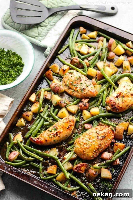 Sheet Pan Honey Garlic Chicken and Roasted Vegetables 4 Hand spooning honey garlic glaze over chicken breasts and vegetables on a baking sheet before roasting.