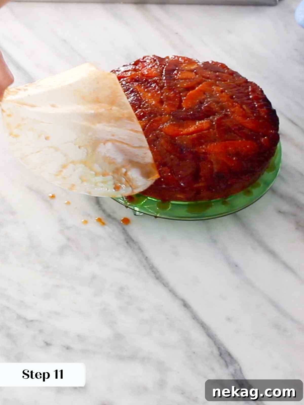 Carefully removing parchment from the top of the inverted upside down cake.