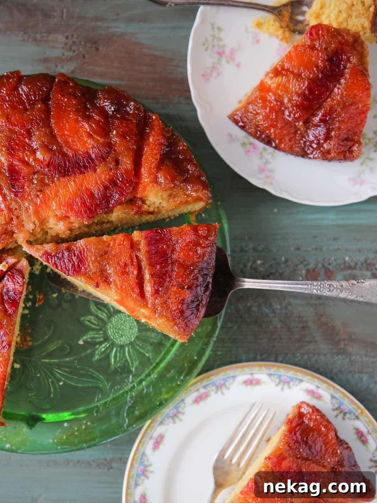 Orange Upside Down Cake displayed beautifully on a green cake plate with vintage plates in the background.