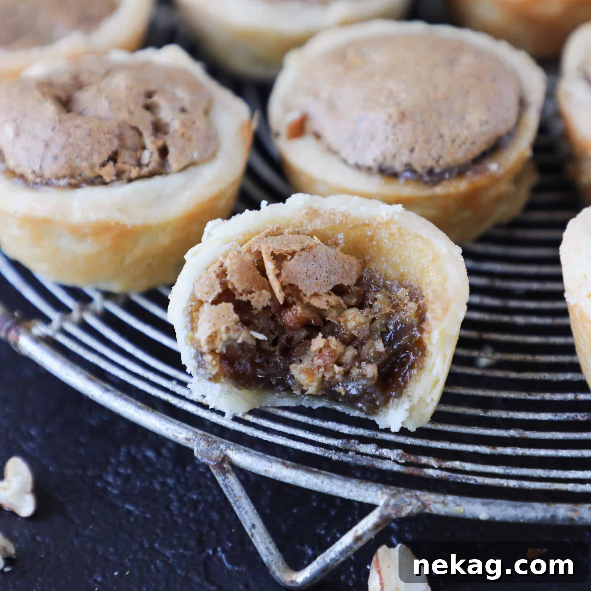 The best pecan tassies on a cooling rack, one delicately bitten to reveal the rich, nutty interior and tender crust.