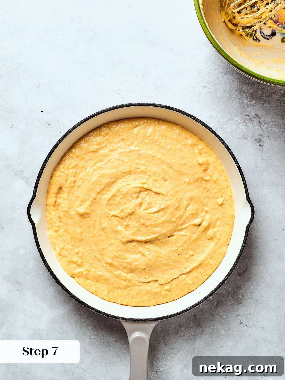 Smooth cornbread batter spread evenly in a prepared cast iron skillet, ready for baking to achieve a perfect crust.
