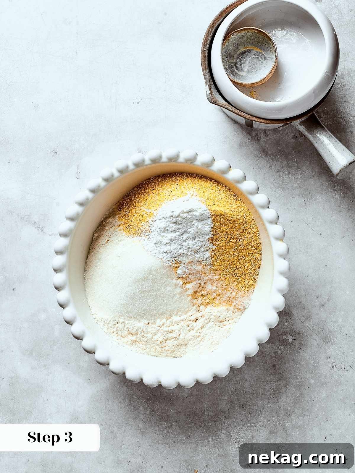Dry ingredients including cornmeal, flour, and salt being thoroughly whisked together in a large bowl, ensuring even distribution.