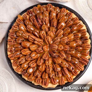 A perfectly baked whole chocolate pecan pie, presented on a round serving board, with a rich golden crust and enticing filling.