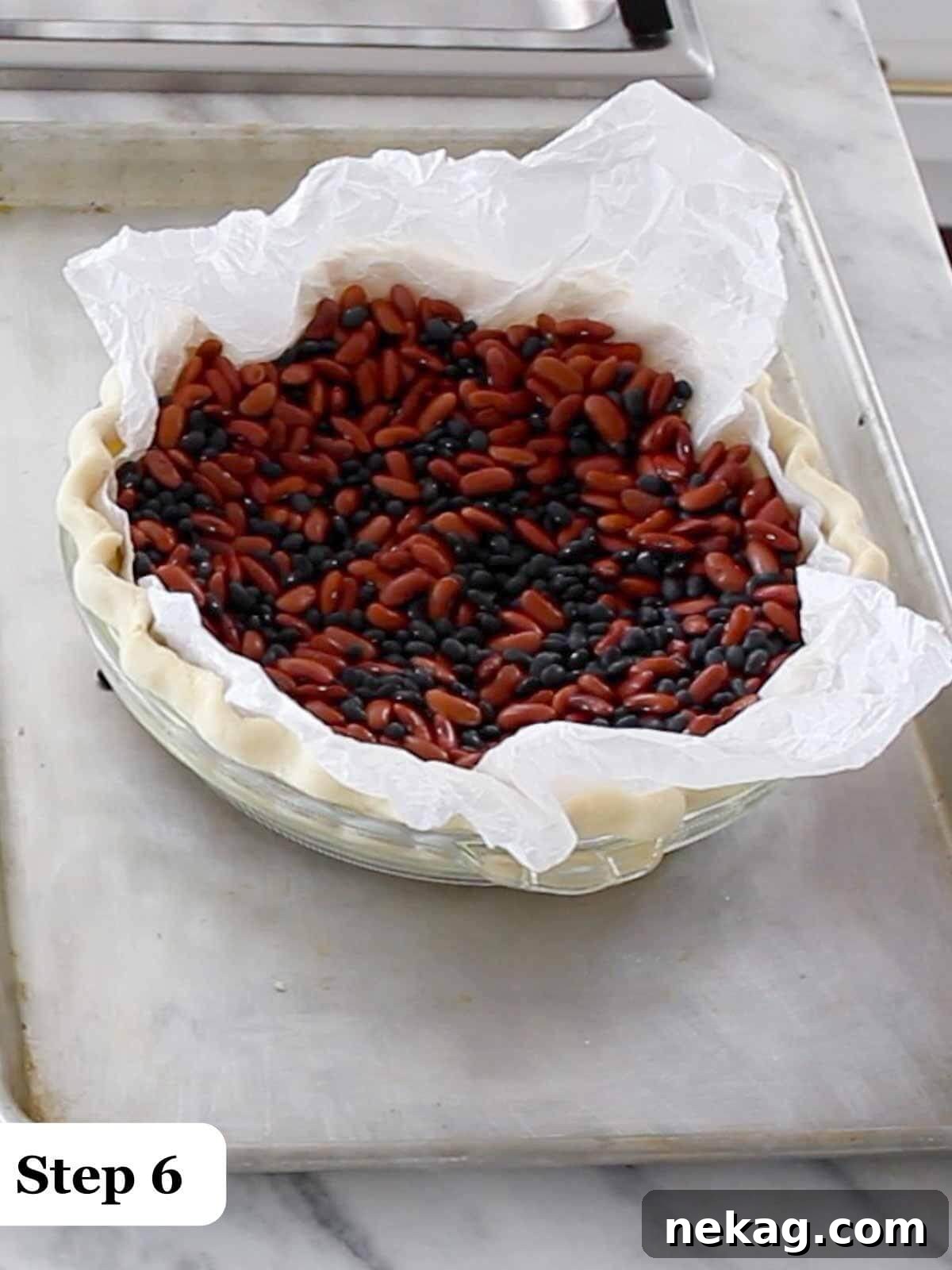 Decadent Chocolate Pecan Pie 7 Step-by-step image demonstrating the use of pie weights, specifically dried beans, to par-bake a pie crust, ensuring an even bake.