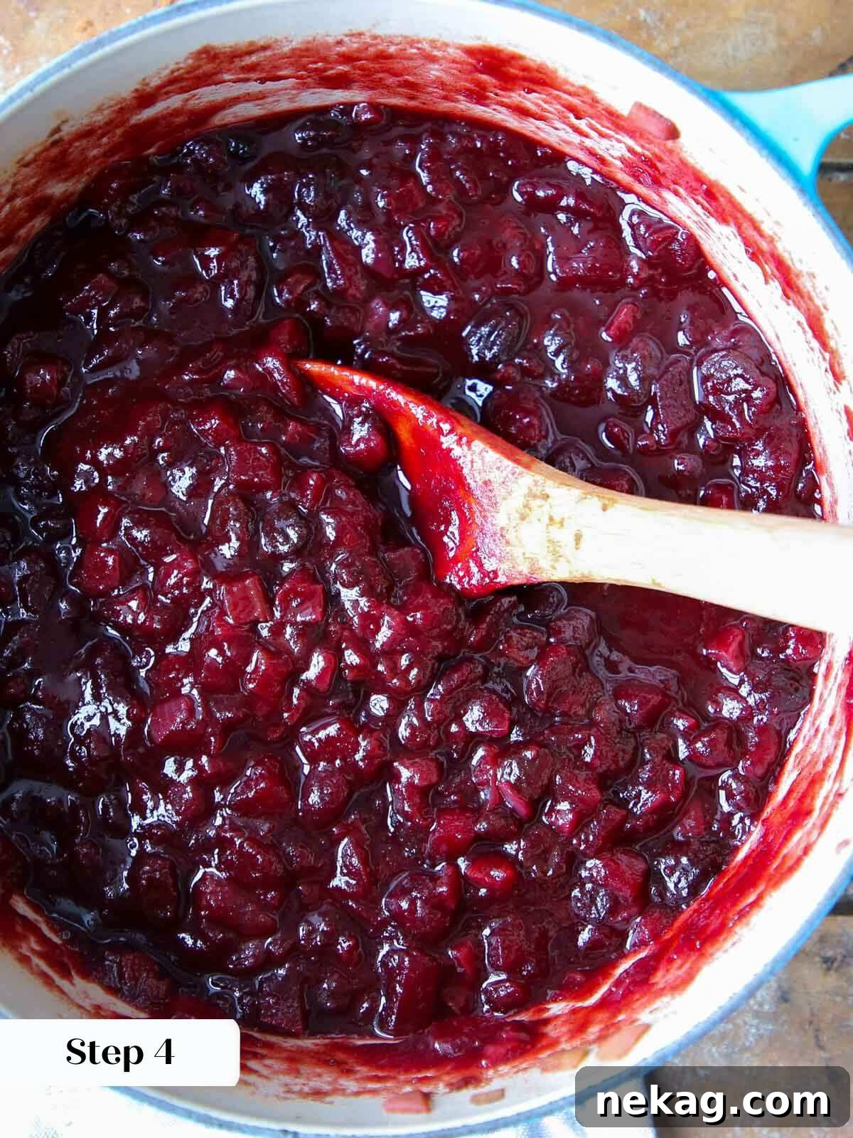 Festive Cranberry Relish 5 Rich, cooked cranberry chutney simmering gently in a pot, with a wooden spoon resting inside, indicating its readiness.