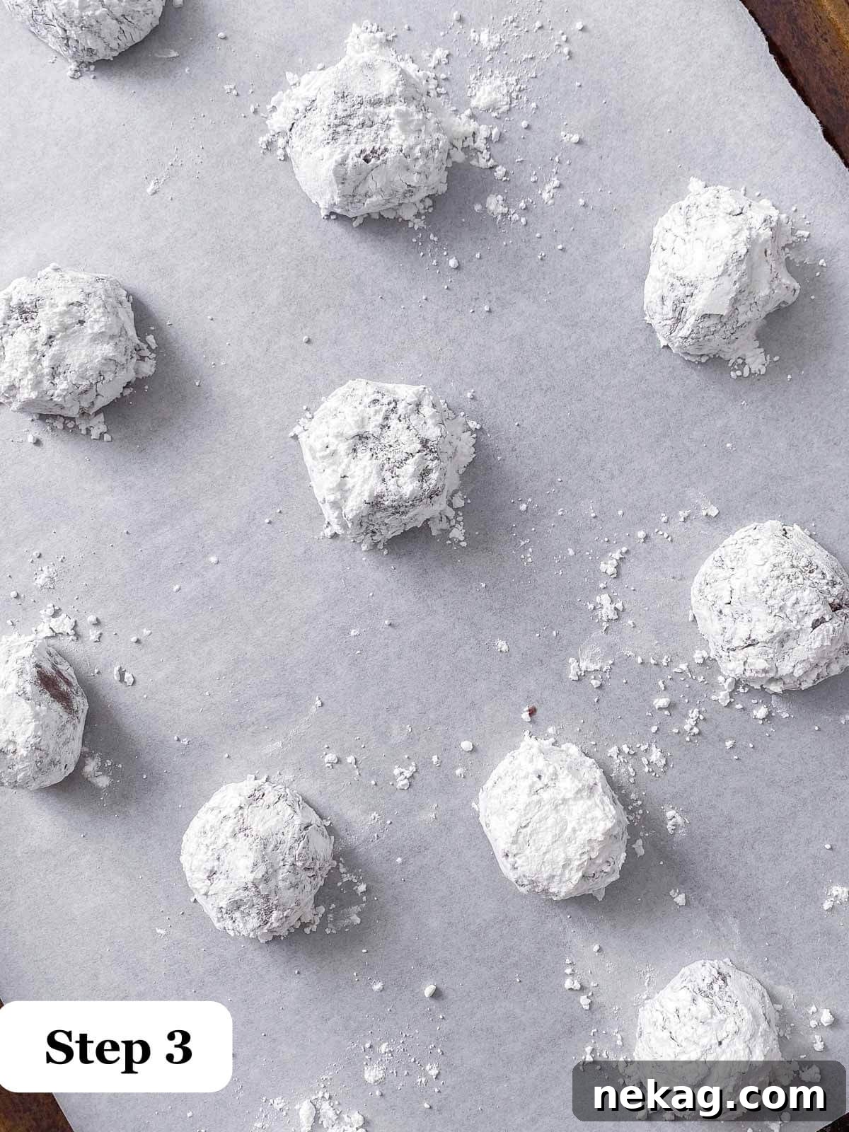 Chocolate cookie dough balls generously rolled in powdered sugar, ready for baking.