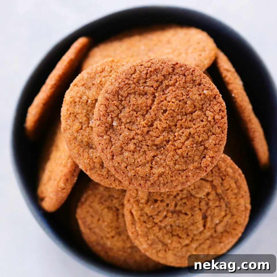 Freshly baked Old Fashioned Gingersnaps on a wire rack, with a distinct cracked top and golden-brown edges, highlighting their crispy texture.