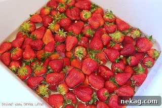 Strawberries soaking in a vinegar and water solution in a sink