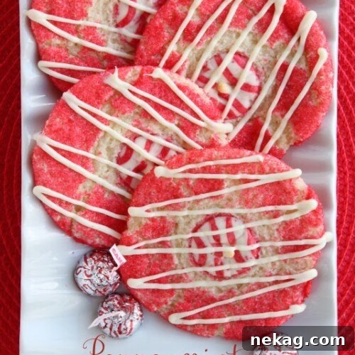 Beautifully decorated Peppermint Thumbprint Cookies, garnished with white chocolate drizzle and red sugar crystals.